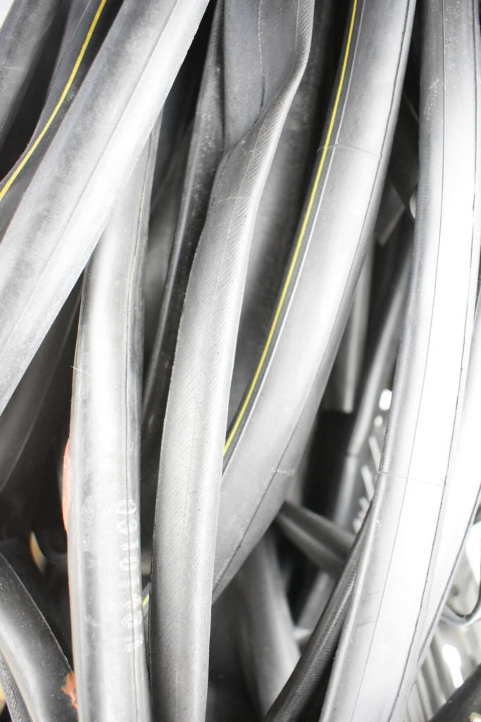 Recyled Jewellery: Close-up photo of black rubber hoses with yellow stripes, likely repurposed from a machine or vehicle's internal system, showing details of texture and folds. @ Reblack Shop